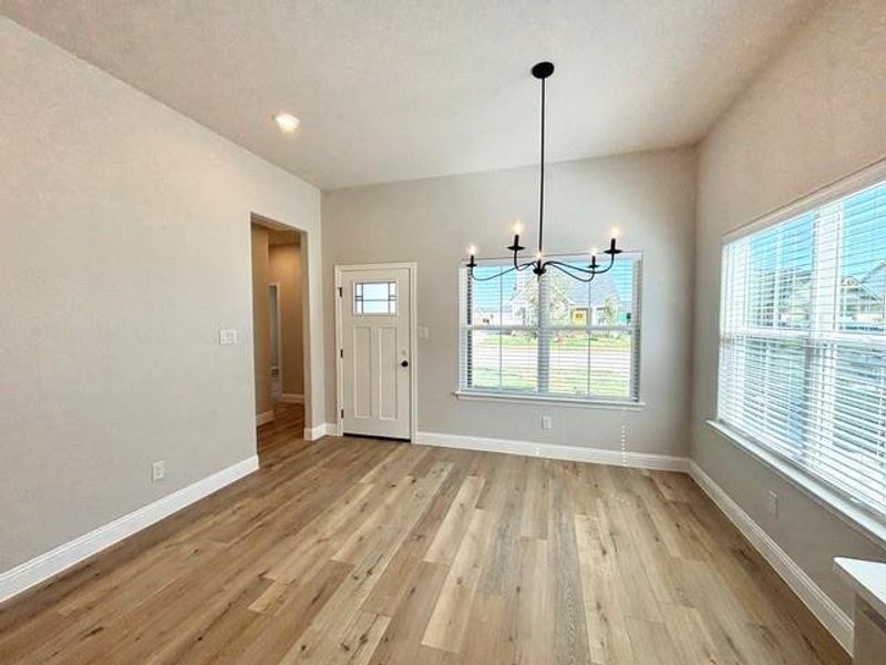 Unfurnished dining area with light hardwood / wood-style floors and a notable chandelier