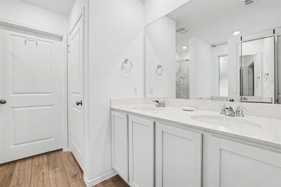 Double vanity with white cabinetry and integrated sinks set in a light-toned countertop