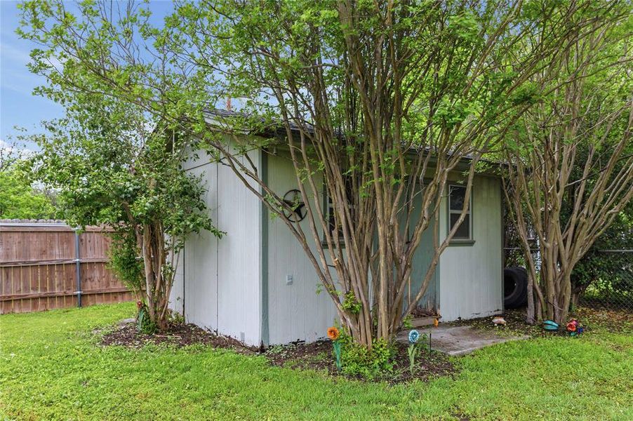 Detached outbuilding featuring vertical siding, a small window, and a concrete pad entry Detached outbuilding featuring vertical siding, a small window, and a concrete pad entry