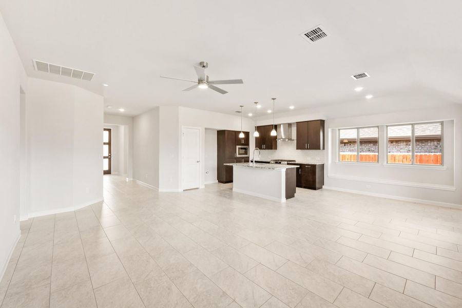 Open-concept living area and kitchen with dark cabinets, center island, tile floors, and ceiling fan Open-concept living area and kitchen with dark cabinets, center island, tile floors, and ceiling fan