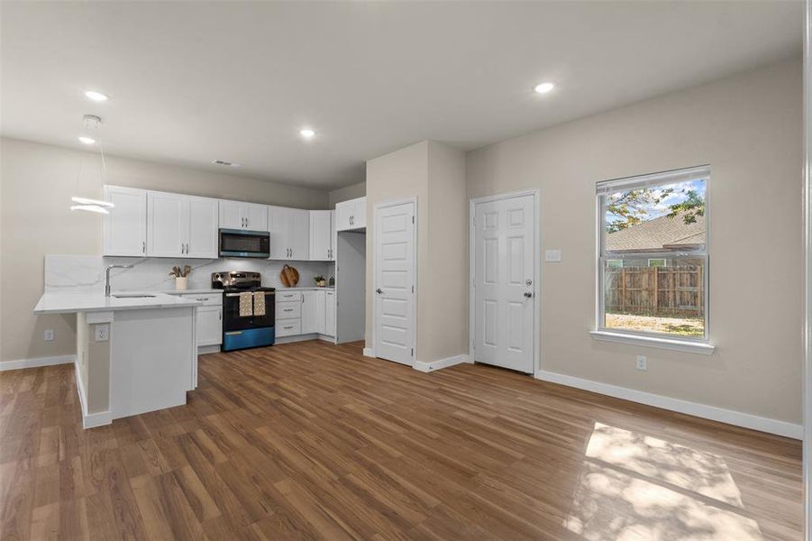 Kitchen featuring a peninsula, white cabinets, electric stove, stainless steel microwave, and dark wood-style flooring Kitchen featuring a peninsula, white cabinets, electric stove, stainless steel microwave, and dark wood-style flooring