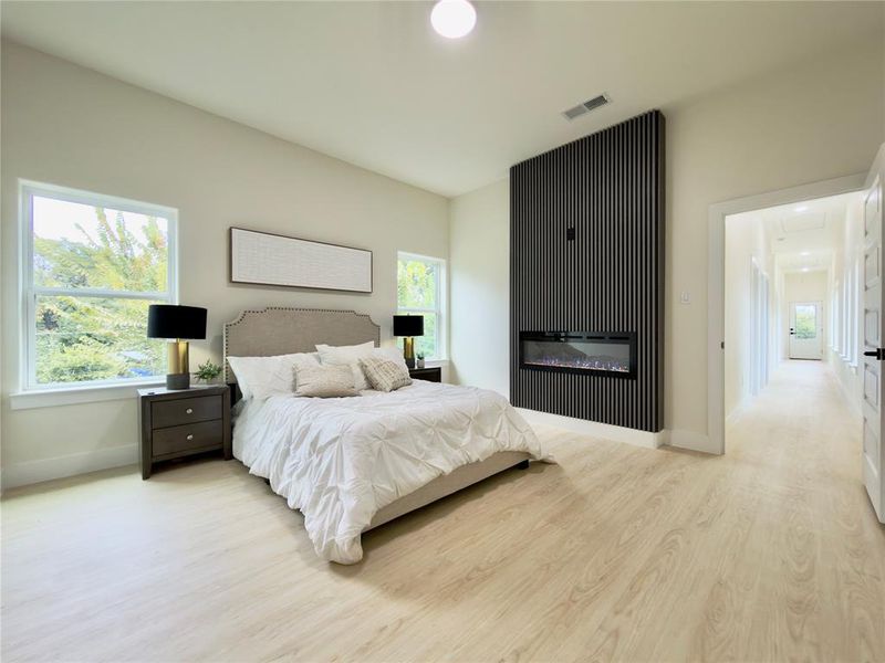 Bedroom featuring multiple windows, light wood-type flooring, recessed lighting, and a glass covered fireplace