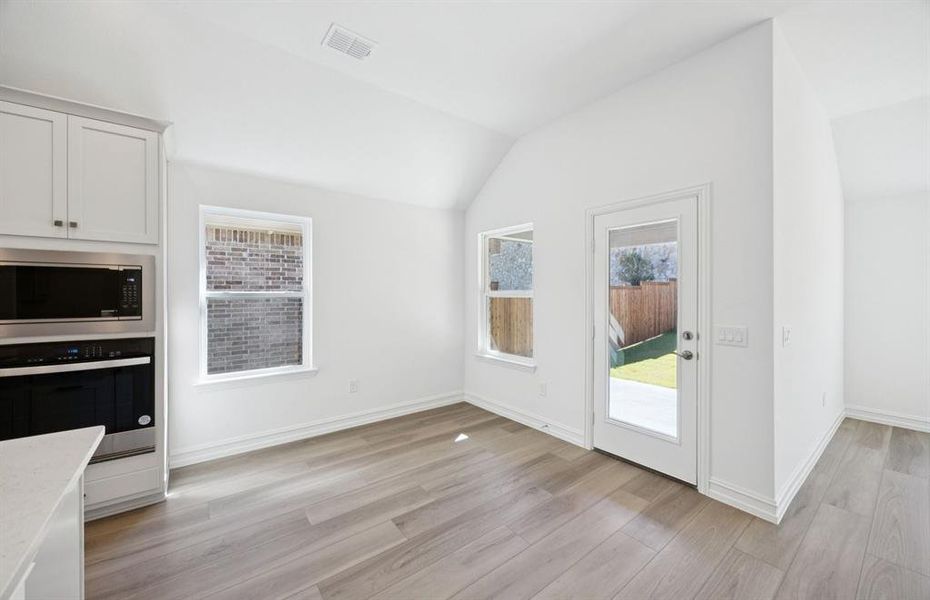 Open kitchen with adjoining nook featuring large windows and direct access to the backyard Open kitchen with adjoining nook featuring large windows and direct access to the backyard