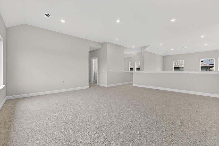 Empty room with light carpet and recessed lighting