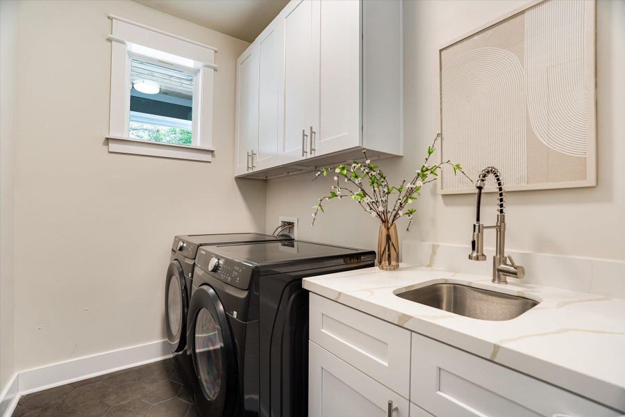 Laundry area featuring a window, white cabinetry, a sink with a gooseneck faucet, and a light-colored countertop Laundry area featuring a window, white cabinetry, a sink with a gooseneck faucet, and a light-colored countertop