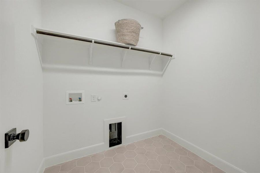 Dedicated laundry space featuring a hexagonal tile floor, white walls, and a built-in shelf with hanging rod