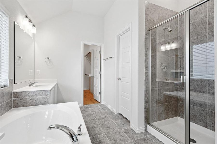 Bathroom featuring large vanity, tile flooring, lofted ceiling, and separate shower and tub