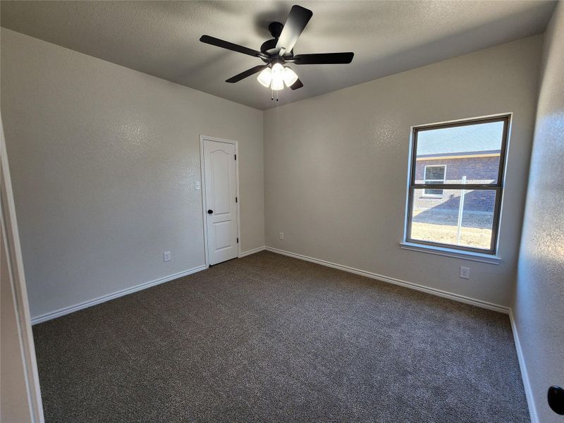 Spare room featuring dark carpet, a textured wall, ceiling fan, and a textured ceiling
