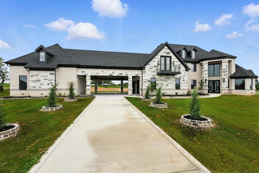 View of front of house with french doors, a front yard, driveway, and stone siding