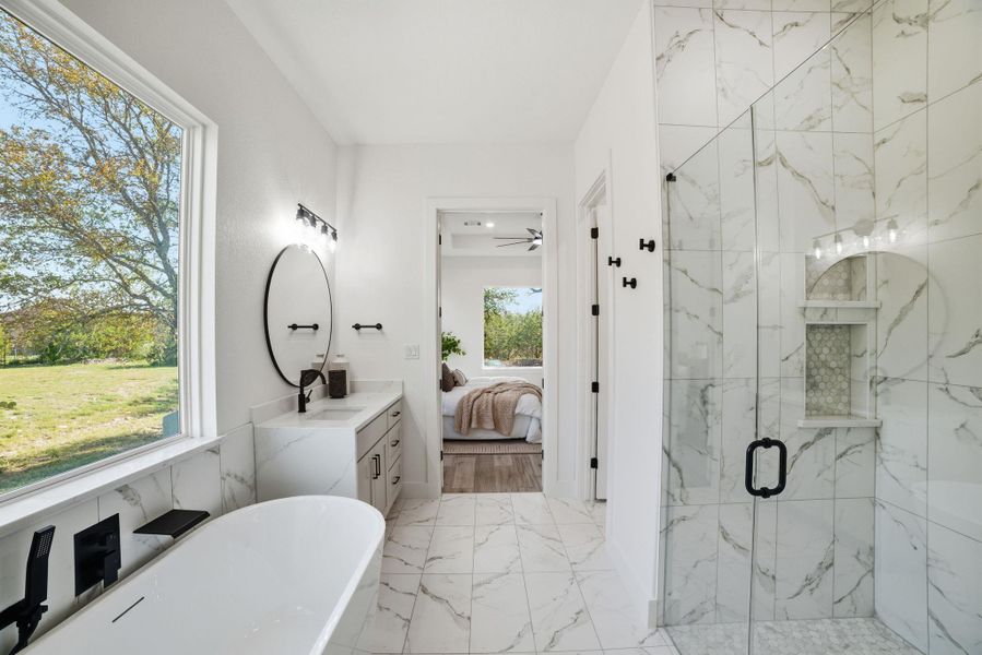 Ensuite bathroom with vanity, light marble finish flooring, a freestanding bath, and a marble finish shower Ensuite bathroom with vanity, light marble finish flooring, a freestanding bath, and a marble finish shower