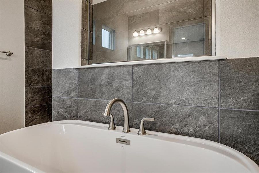 Bathroom featuring tile walls, a bathing tub, and sink