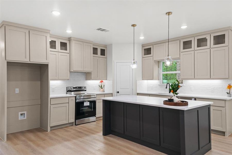 Kitchen featuring a spacious island with a white countertop, two-tone cabinetry, stainless steel range, wood-finish flooring, and pendant lighting Kitchen featuring a spacious island with a white countertop, two-tone cabinetry, stainless steel range, wood-finish flooring, and pendant lighting