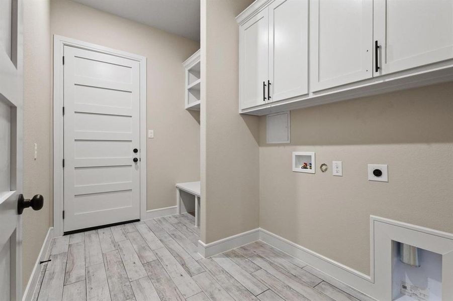 Laundry area featuring light wood-style flooring, hookup for an electric dryer, hookup for a washing machine, and cabinet space
