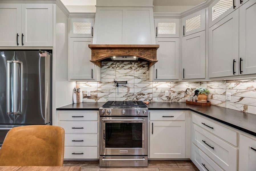 Look at this Stunningly Beautiful Kitchen! Custom lighting throughout the cabinets, above, inset and under. Black Leathered Granite countertops, Quartz backsplash, butcher block island topper, pot filler, gas cook top and range and more!