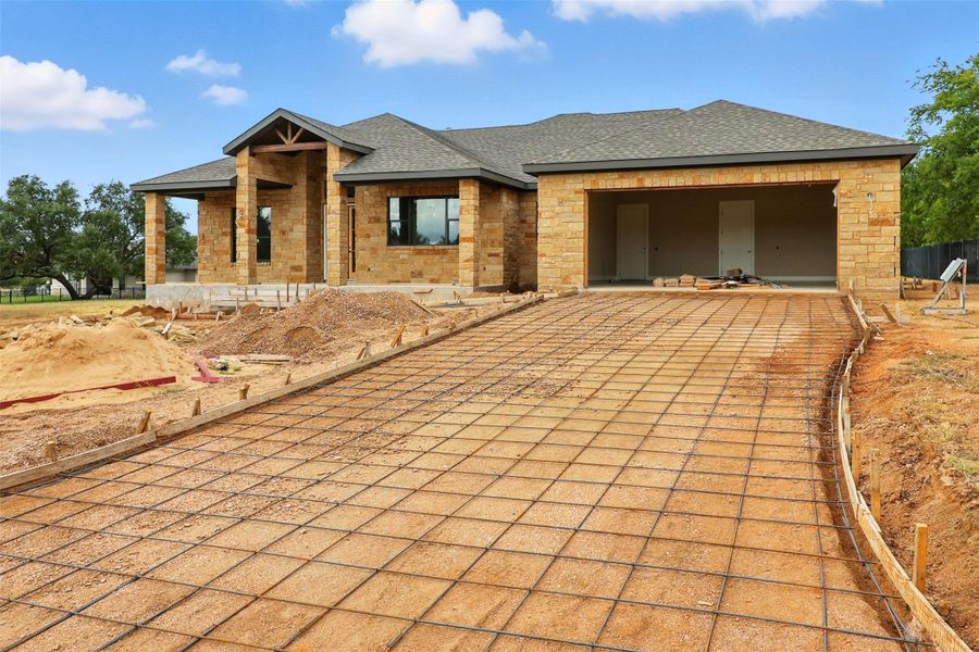 View of front of property featuring a shingled roof, an attached garage, decorative driveway, and stone siding View of front of property featuring a shingled roof, an attached garage, decorative driveway, and stone siding