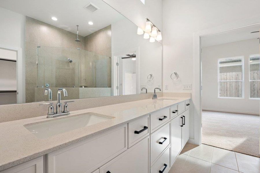 Full bathroom featuring light carpet, a shower stall, double vanity, light tile patterned floors, and ceiling fan