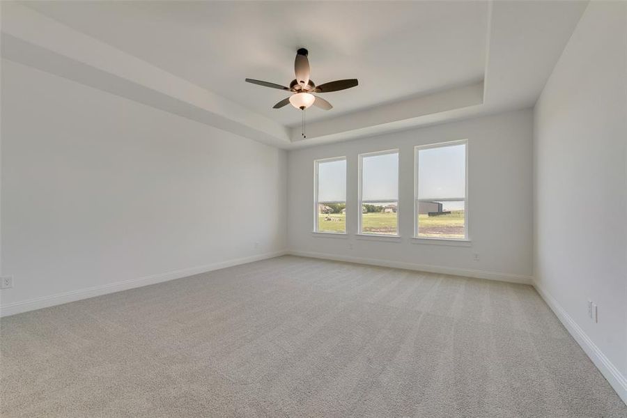 Carpeted empty room with a tray ceiling and ceiling fan