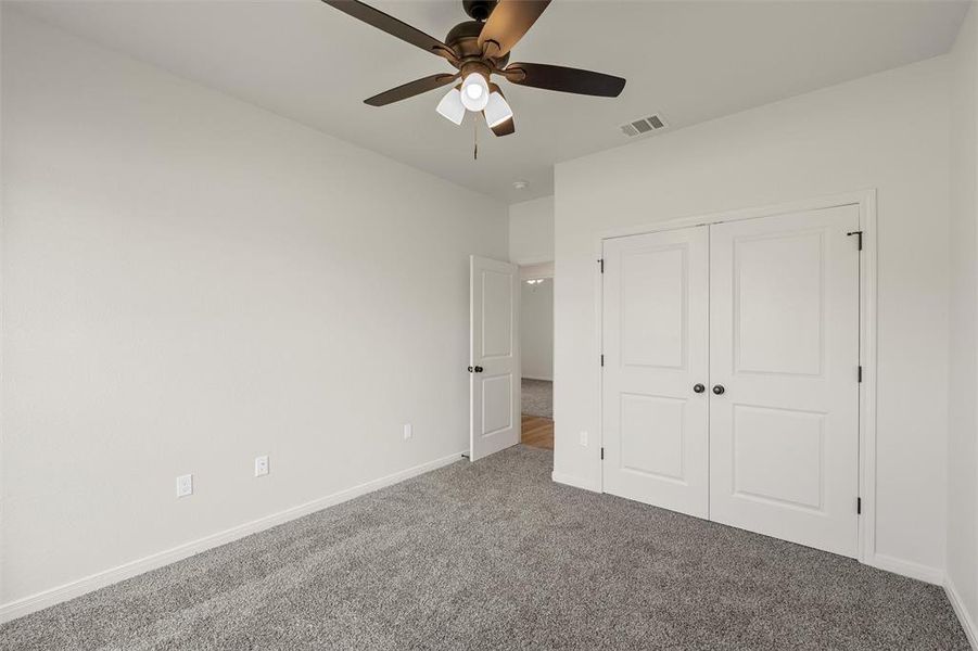 Unfurnished bedroom with carpet floors, a closet, and a ceiling fan Unfurnished bedroom with carpet floors, a closet, and a ceiling fan