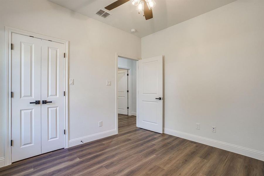 Unfurnished bedroom with dark wood-type flooring, a ceiling fan, and a closet
