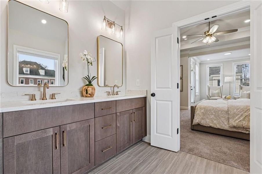 Ensuite bathroom featuring healthy amount of natural light, double vanity, recessed lighting, a ceiling fan, and light carpet