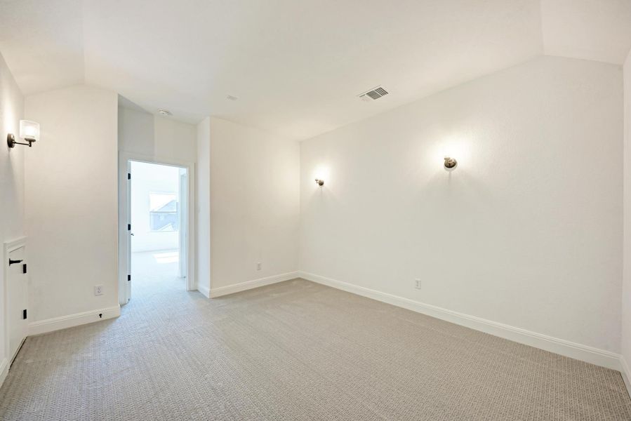 Empty room with lofted ceiling and light colored carpet
