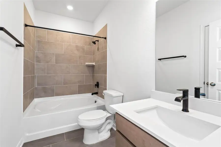 This move-in ready primary bathroom offers a spacious tub/shower combination with a tiled surround, stained cabinetry topped with light countertops, high ceilings, neutral paint, a mirror, and sleek, modern finishes for a polished look. This move-in ready primary bathroom offers a spacious tub/shower combination with a tiled surround, stained cabinetry topped with light countertops, high ceilings, neutral paint, a mirror, and sleek, modern finishes for a polished look.