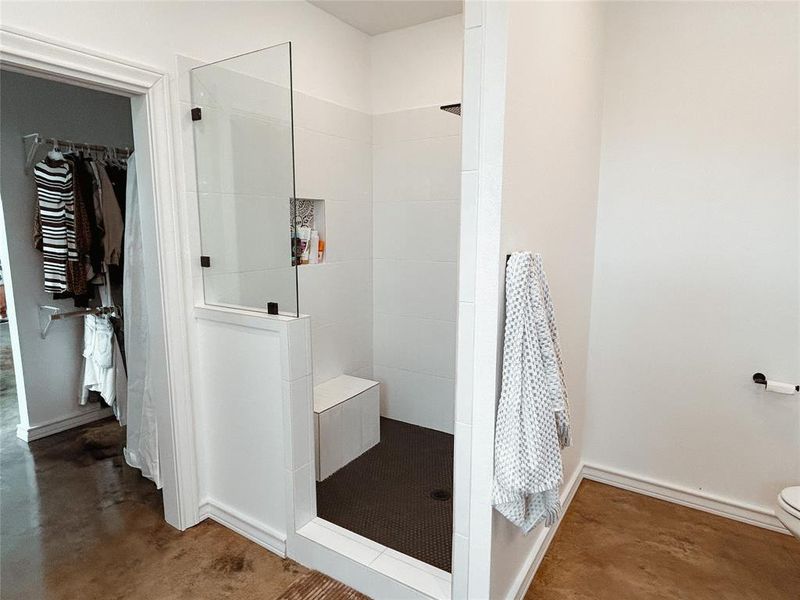 Bathroom featuring a walk in shower, a walk in closet, and finished concrete floors Bathroom featuring a walk in shower, a walk in closet, and finished concrete floors