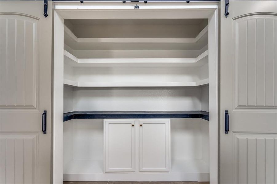 View of pantry with barn doors open. TONS of shelving and more cabinets underneath all add up to the perfect accompaniment to this stunning kitchen.