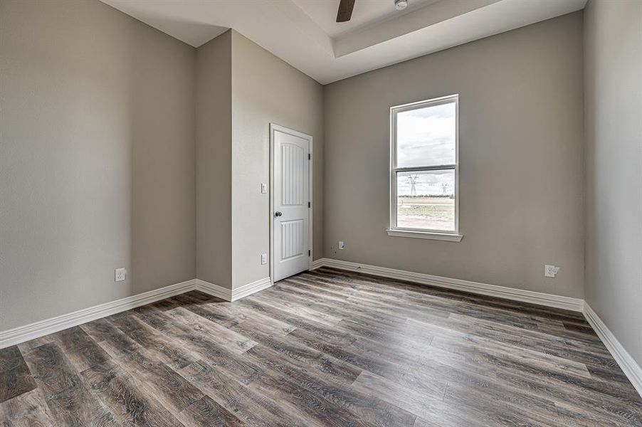 Empty room featuring ceiling fan, a tray ceiling, and hardwood / wood-style flooring