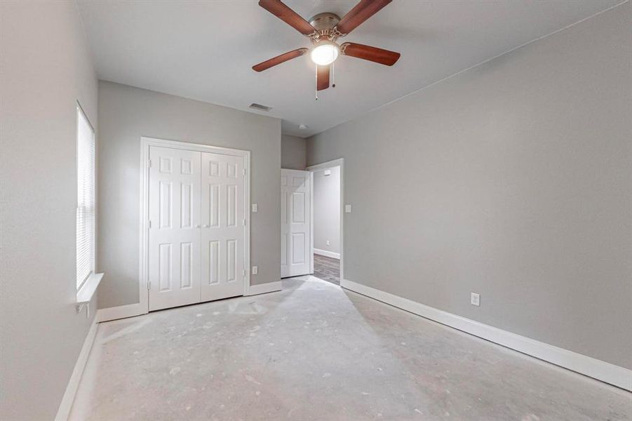 Unfurnished bedroom featuring a closet, concrete floors, and ceiling fan