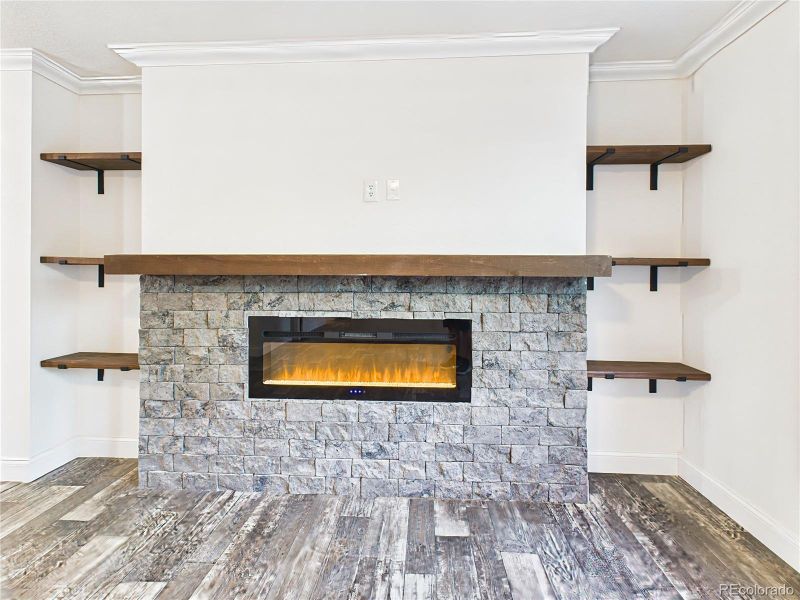 Striking stone accent wall with linear electric fireplace and custom wood shelving.