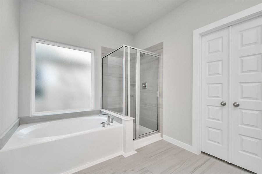 The primary en-suite has a soaking tub to give you that spa experience. The large privacy window allow lots of nature light in the space. Sample photo of completed home with similar floor plan. As-built interior colors and selections may vary.