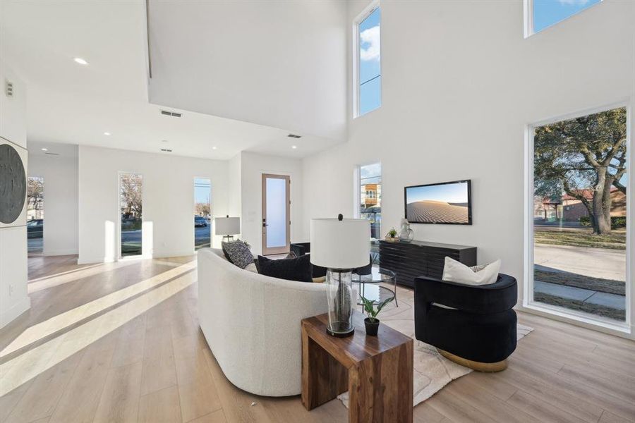 Living room with light hardwood / wood-style floors and a high ceiling