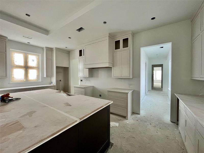 Kitchen with white cabinetry and custom exhaust hood