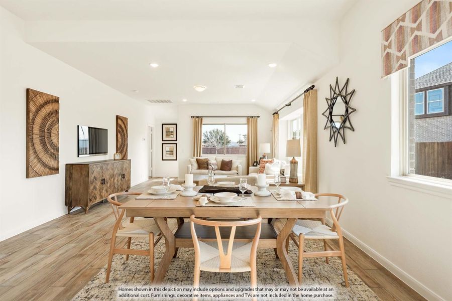 Open-plan dining room with wood table and chairs flowing into living room with hardwood floors and white walls