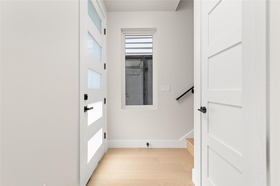 Clean lines and light wood flooring define this modern entryway transition to the staircase.