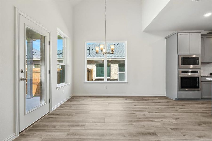 Unfurnished dining area featuring a chandelier and light wood-style flooring Unfurnished dining area featuring a chandelier and light wood-style flooring