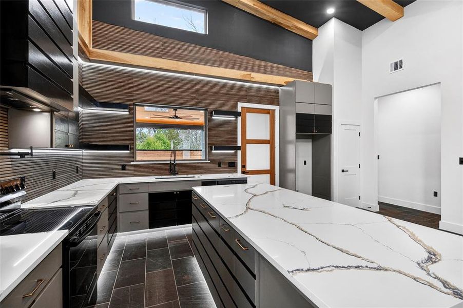 Kitchen featuring black / electric stove, light stone counters, gray cabinetry, dark cabinetry, and recessed lighting