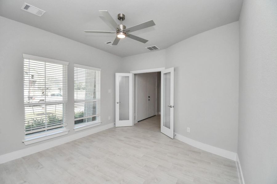 Experience the perfect blend of sophistication and warmth in this home office, boasting elegant wood-look tile flooring and flooded with natural light from expansive windows and French doors. Sample photo of completed home with similar floor plan. Actual colors and selections may vary.