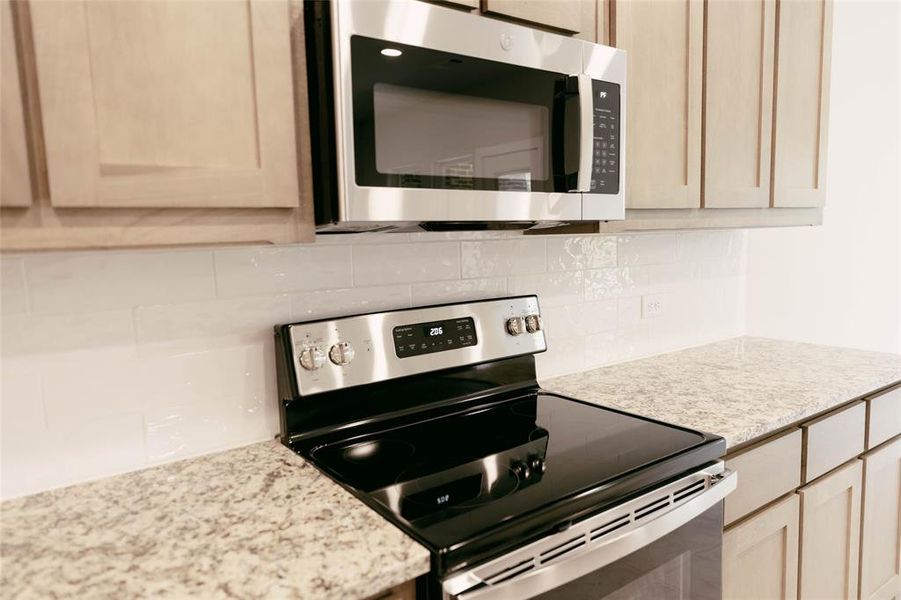 Kitchen with light brown cabinets, tasteful backsplash, and stainless steel appliances