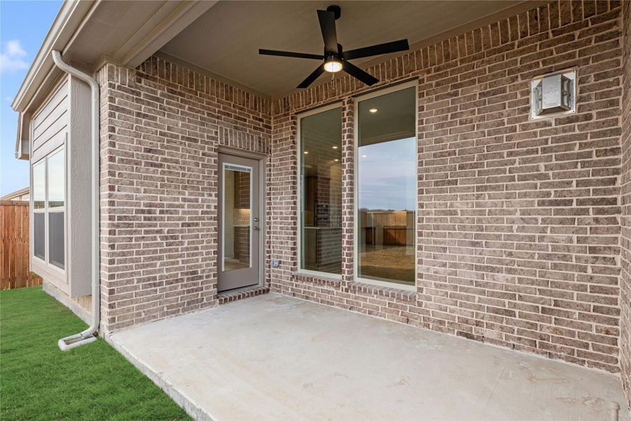 Covered back patio with ceiling fan, brick exterior, concrete slab, and glass door entry Covered back patio with ceiling fan, brick exterior, concrete slab, and glass door entry