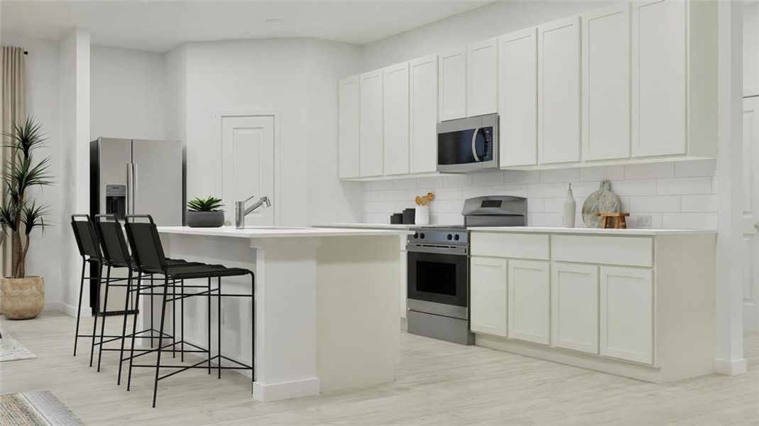 Kitchen featuring appliances with stainless steel finishes, backsplash, an island with sink, a kitchen bar, and white cabinetry Kitchen featuring appliances with stainless steel finishes, backsplash, an island with sink, a kitchen bar, and white cabinetry