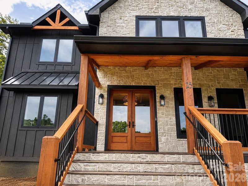 Inviting covered front porch with natural wood accents and custom entry doors