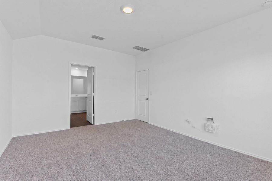 Unfurnished bedroom with lofted ceiling, dark carpet, visible vents, and baseboards