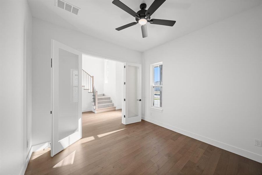 Empty room with stairs, wood-type flooring, and ceiling fan