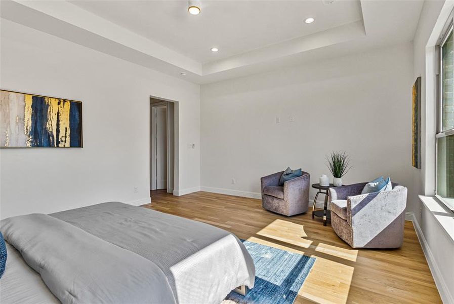 Bedroom with light hardwood / wood-style floors and a raised ceiling