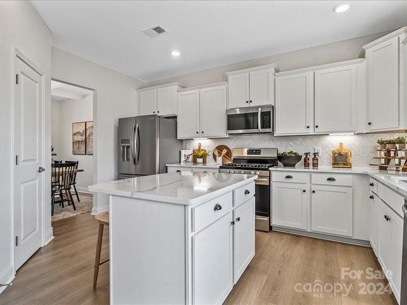 PHOTO REPRESENTATION ONLY. Kitchen of decorated model home. Finishes are different than shown. Refer to the interior design selections for finishes. Refrigerator not included.