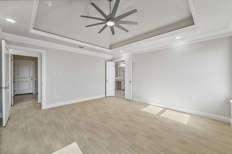 Unfurnished room with a raised ceiling, recessed lighting, ornamental molding, light wood-style flooring, and ceiling fan