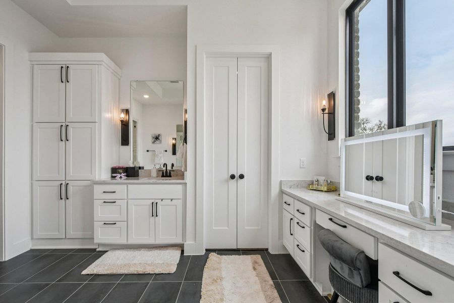 Bathroom featuring dark tiled flooring, white cabinetry, a sink vanity with a mirror, and a vanity area with a large window Bathroom featuring dark tiled flooring, white cabinetry, a sink vanity with a mirror, and a vanity area with a large window