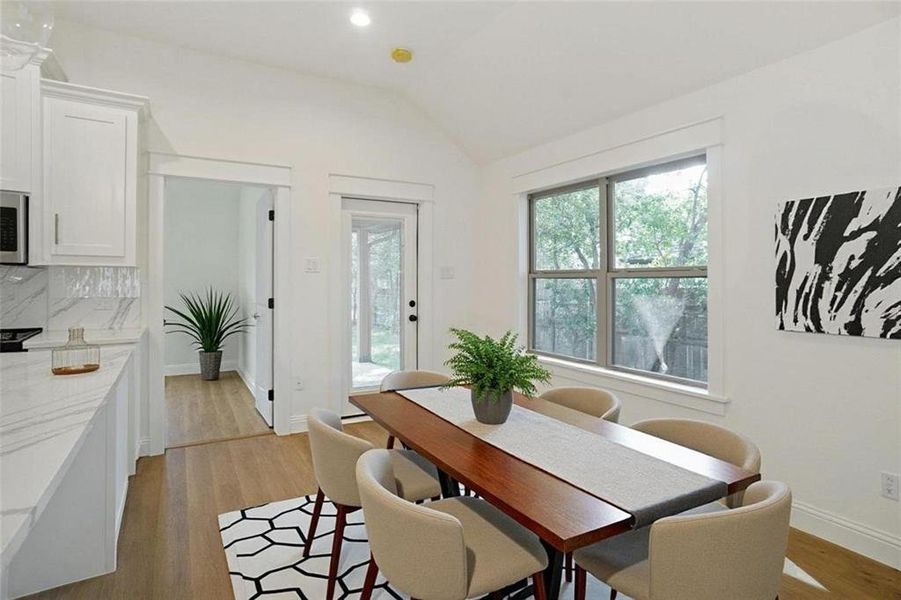 Dining space with light wood-type flooring, vaulted ceiling, and recessed lighting